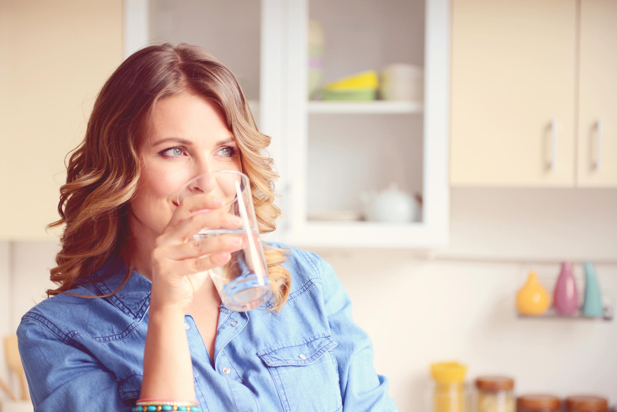Почему за 30 минут до еды. Женщина пьет воду. Женщина со стаканом. Девушка пьет воду на кухне. Девушка со стаканом воды на кухне.